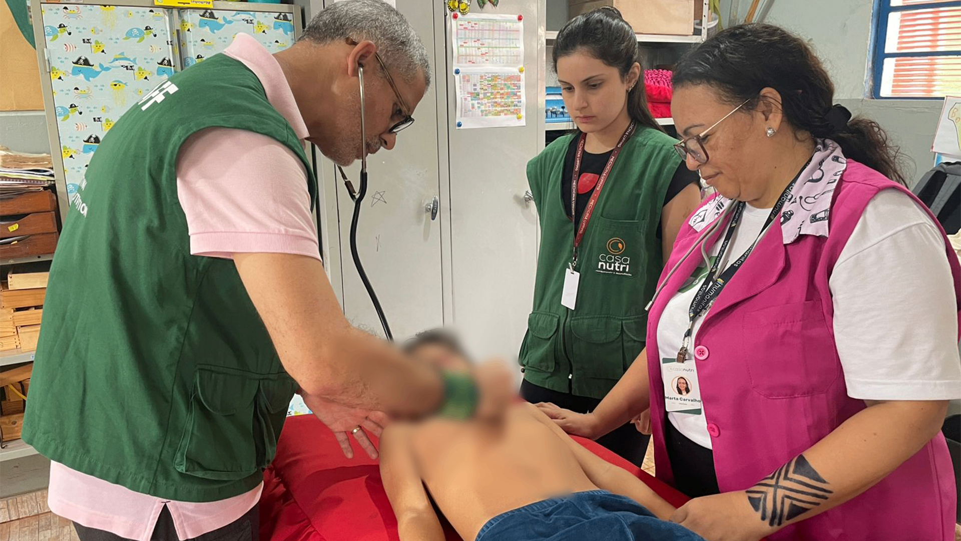 Equipe médica auscultando criança indígena
